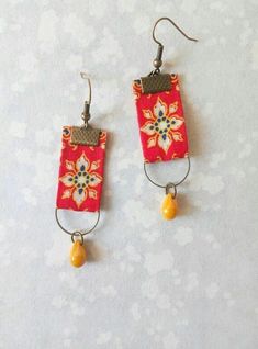 the earrings are decorated with red and orange designs on them, along with yellow beads