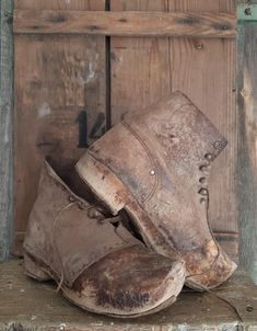 an old pair of dirty shoes sitting on top of a wooden shelf next to a door