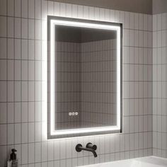 a bathroom sink with a lighted mirror above it and a bathtub in the background