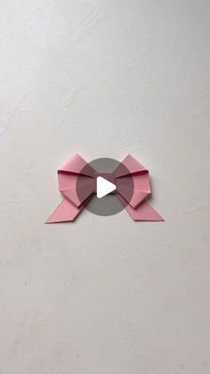 an origami clock with a pink bow on the front and grey back side