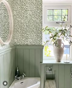 a white sink sitting under a bathroom window next to a bathtub and toilet paper dispenser