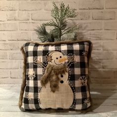 a snowman pillow sitting on top of a white brick wall