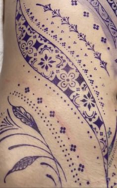 a woman's stomach with tattoos on it and an intricate design in the belly