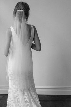 a woman in a wedding dress looking at her veil