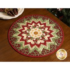 a red and green rug sitting on top of a wooden table next to a christmas tree