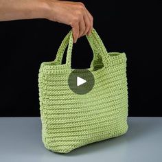 a person is holding a green bag with a video playing button on the front and side