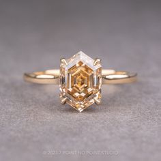 an engagement ring with a fancy yellow diamond in the center, on a gray surface