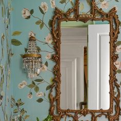 a mirror on a wall with flowers painted on it and a chandelier hanging from the ceiling