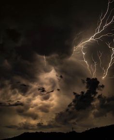 a lightning bolt is seen in the sky above some dark clouds and water at night