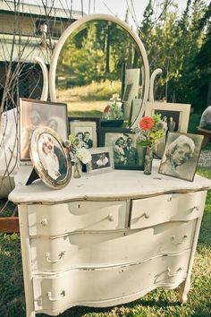 an old dresser with pictures and frames on it