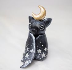 a small figurine with stars and a moon on it's head, sitting in front of a white background