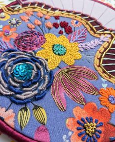 an embroidered purse with flowers and leaves on the front, sitting on top of a table