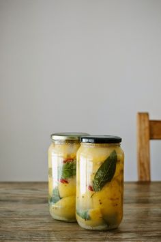 two jars filled with pickles sitting on top of a wooden table