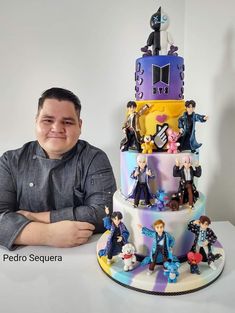 a man sitting in front of a multi layered cake with figurines on it