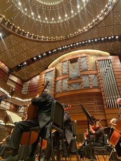 an orchestra playing in front of a concert hall with string lights hanging from the ceiling