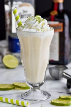 a drink in a glass with whipped cream and limes