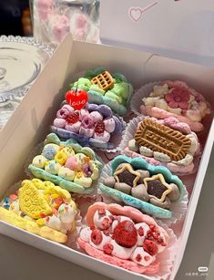 a box filled with lots of different types of cookies on top of a table next to plates