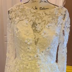 a white wedding dress on display in front of a yellow door with the words, i do