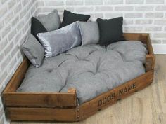 a dog bed made out of an old wooden crate with pillows on the top and bottom