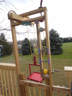 a wooden play set with swings and toys on it's back deck in the yard