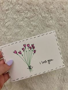 someone is holding up a card that says i love you with pink flowers on it