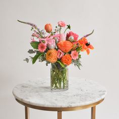 an arrangement of flowers in a glass vase on a marble table