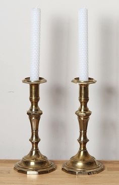 two brass candlesticks sitting on top of a wooden table