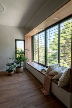 there is a window seat with pillows on it in the room that has wooden flooring