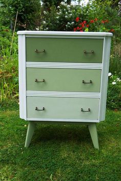 a green and white dresser sitting in the grass