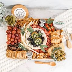 a platter filled with cheeses, crackers, olives and other foods