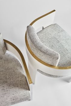 an upholstered chair with a curved seat and gold trim around the armrests