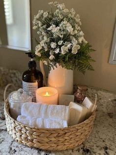 a basket filled with lots of white flowers next to a candle and some soaps