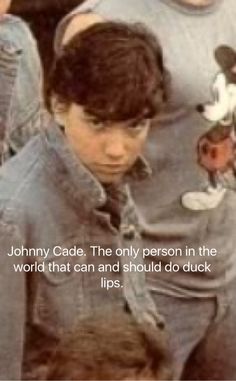 an image of a young boy holding a teddy bear in front of other people with the caption johnny caddie, the only person in the world that can and should do duck lips