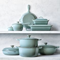 various pots and pans on shelves with white wall in the backgrounnd