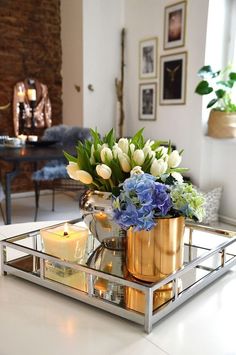 a tray with flowers and candles in it on a table next to a couch or chair