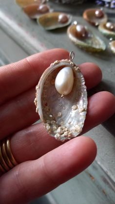 a person holding a shell with a pearl in it