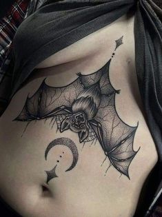 a woman's stomach with a bat and crescent moon tattoo on the side,