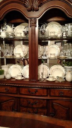 a wooden china cabinet filled with dishes and glasses