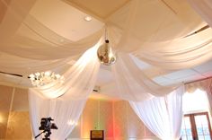 a room decorated with white drapes and chandeliers