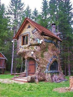 a tree house built into the side of a large tree trunk in a wooded area