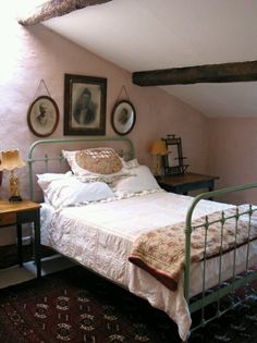 a bed sitting in a bedroom next to two framed pictures on the wall above it