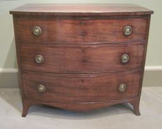 an antique chest of drawers with brass knobs on the top and bottom, against a beige wall