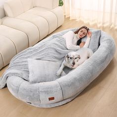 a woman laying on top of a dog bed with a large white dog in it