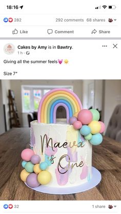 a cake that is sitting on top of a table with balloons and rainbows around it