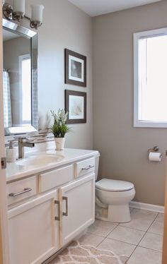 a bathroom with a toilet, sink and large mirror in it's center area