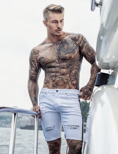 a man with tattoos standing on a boat