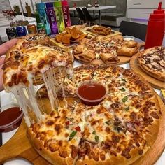 several pizzas on wooden platters with sauce and condiments sitting on the table