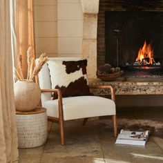 a chair sitting in front of a fireplace with a cow hide pillow on it's back