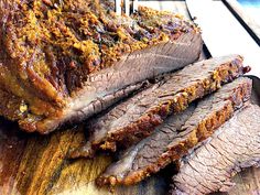 sliced meat sitting on top of a wooden cutting board next to a knife and fork