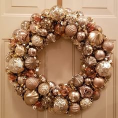 a christmas wreath is hanging on the front door, with ornaments all over it's frame